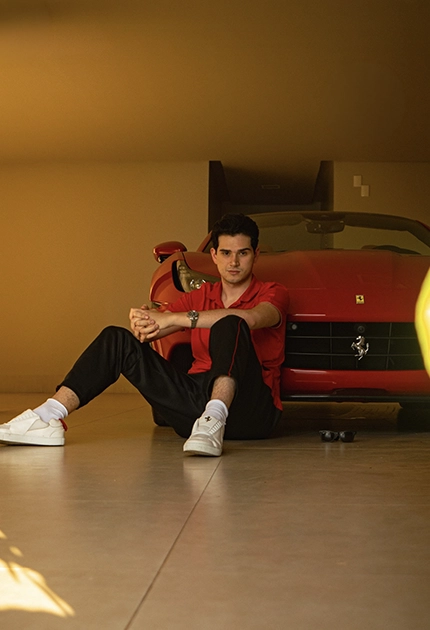 André Victor sentado ao lado de uma Ferrari